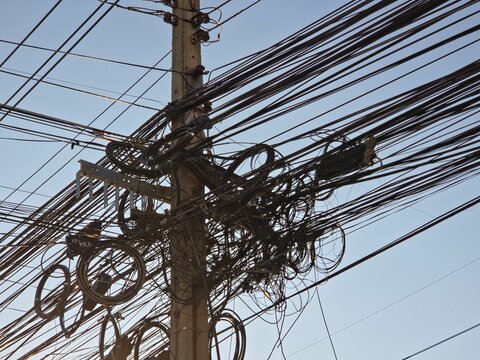 Tangled Mess of Electrical and Communication Cables on Concrete Power Pole in Thailand