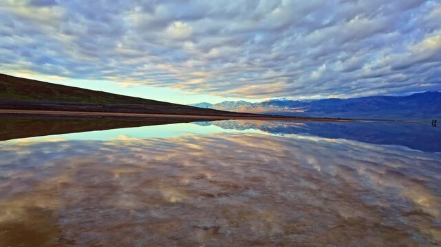 Panoramic mountain range reflecting in still mirror waters at Badwater Basin Death Valley California