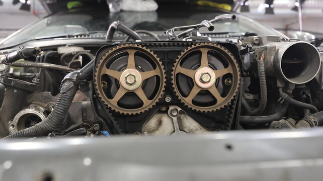 Close-up of a car engine with exposed timing gears and dual overhead camshafts