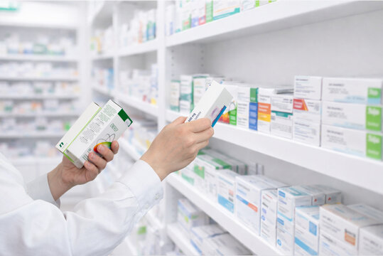 Pharmacist selecting medicine box from shelf in pharmacy, healthcare and retail drugstore concept