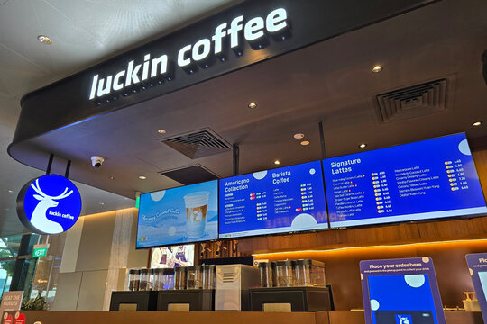 Changi, Singapore - Jan 14, 2026: A modern Luckin Coffee outlet storefront featuring a blue circular deer logo and digital menu boards displaying coffee selections at Singapore Changi Airport terminal