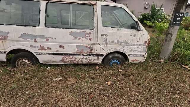 Abandoned and rusted white van sinking into the ground 