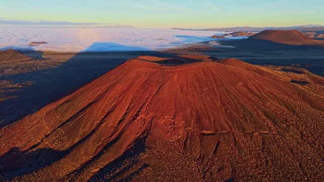 Scenic aerial perspective of volcanic cinder cones in Mojave Desert illuminated by golden sunrise light