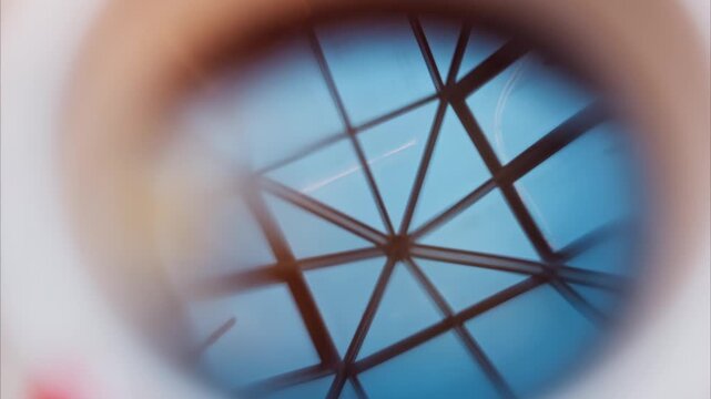 Abstract geometric pattern, blue sky and structural lines viewed through a round lens, slow motion.