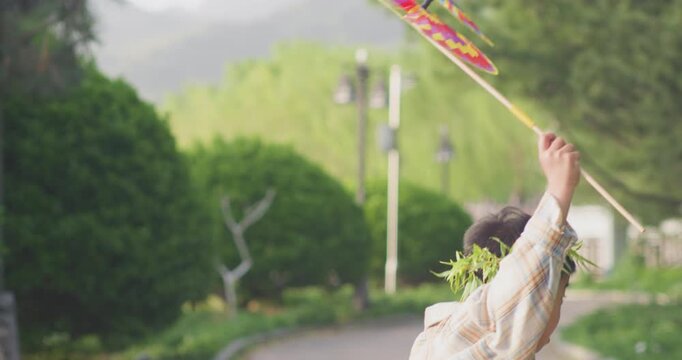 A Chinese mother and child play outdoors wearing willow leaf-woven clothes.