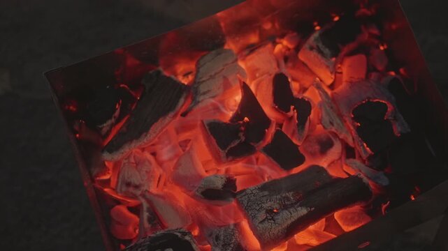 Glowing ember scenes. Bright glowing coals crackle with intense heat during camping adventures. Close up view of sizzling glowing coals illuminating outdoor cooking and camping atmospheres