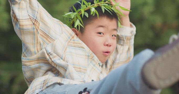 A Chinese mother and child play outdoors wearing willow leaf-woven clothes.