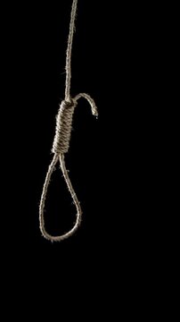 Rope noose swinging to camera and slowly coming to rest on a dark background. Dramatic and symbolic imagery representing tension, danger, fear, or dark themes, suitable for cinematic and conceptual us