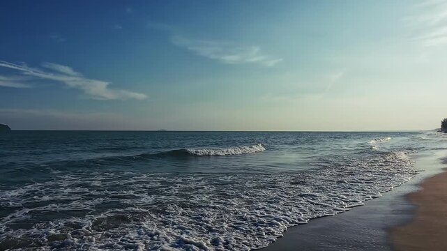 Evening ocean waves roll onto sandy shore as camera pans from shore silhouetted palm against sun to sea distant islands reveal tranquil coastal beauty and natural water texture