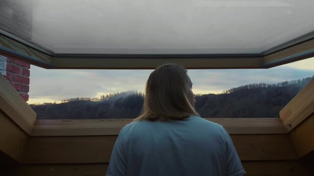Man looking attic window enjoying sunrise morning light at home
Young man looking t panoramic attic window and enjoying soft sunrise light. Cozy home lifestyle and peaceful morning routine atmosphere.