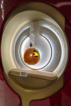 Changi, Singapore - Jan 14, 2026: Close-up of a luxury Louis XIII de Remy Martin Cognac crystal decanter showcased in an illuminated circular gold and red display at a duty-free shop in Changi Airport