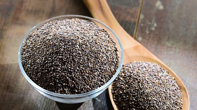 Bowl of chia seeds on wooden table.
