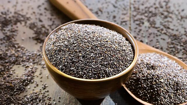 Bowl of chia seeds on wooden table.