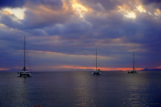 Three catamaran sailing yachts at sunset, in cloudy weather, in Glyfada, Greece