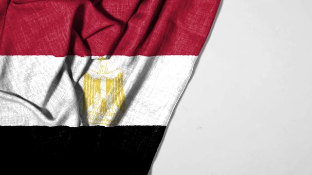 Egyptian flag featuring red, white, and black horizontal stripes, adorned with the golden eagle emblem, displayed on a flowing fabric surface