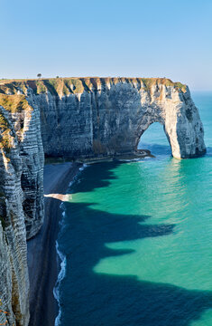 Chalk cliffs of Etretat rise above the blue waters in Normandy France