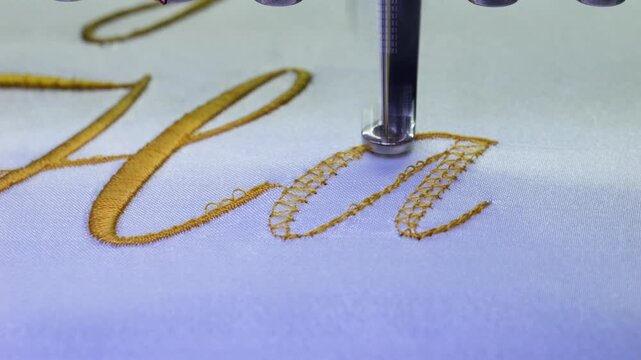 Machine embroidery of text with gold thread on a white satin robe. Preparation for the wedding day. Elegant bridal lingerie. Close-up.
