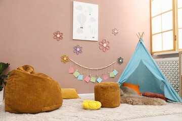 Colorful paper notes and beautiful decor hanging on beige wall near toy wigwam in stylish children's room. Interior design © New Africa