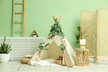 Cute wigwam with leaves and blanket in stylish child's room © New Africa
