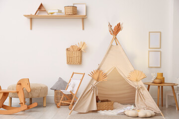 Stylish wigwam with dry leaves in child's room. Space for text © New Africa