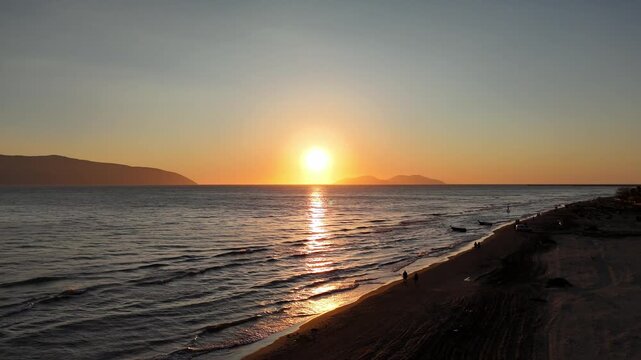 Aerial drone view of coastal sea at sunset with warm light and scenic horizon.