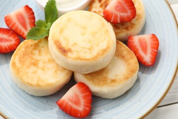 Delicious cottage cheese pancakes with strawberries and mint on plate, closeup
