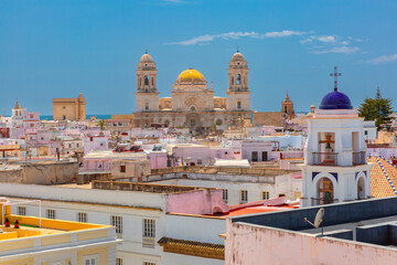 Panoramic view of Cadiz skyline in Spain, with colorful rooftops and Cadiz Cathedral rising above the historic old town under clear blue sky. © Kavalenkava