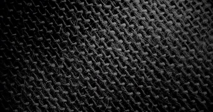 Slow Diagonal Pan Over Black Woven Texture. Smooth slow diagonal movement across extreme close-up of coarse black woven fabric with visible threads and dramatic side lighting.