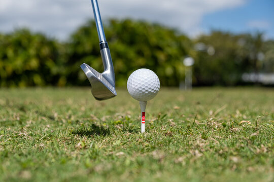 A dynamic, mid-action shot of a golfer performing a powerful swing with a driver. The image captures the follow-through motion against a vibrant green fairway and a clear blue sky