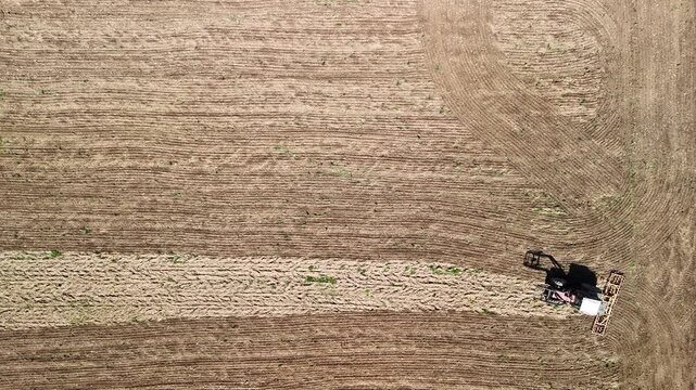 Aerial Drone View of Tractor Plowing Agricultural Field with Patterned Farmland