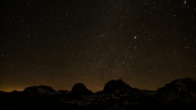 A vast, starry sky illuminates silhouetted mountains. The celestial expanse is filled with countless stars, creating a breathtaking and awe-inspiring nocturnal vista.