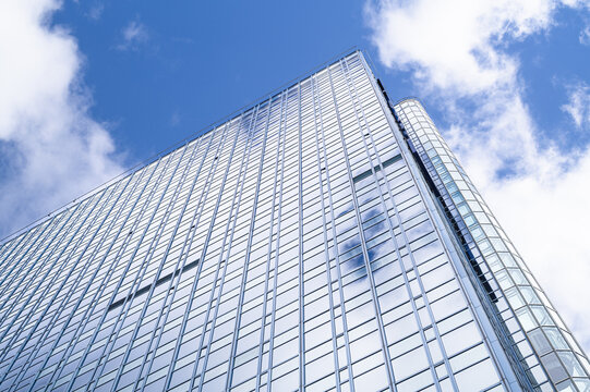 Tall modern business building towering against the blue sky with clouds