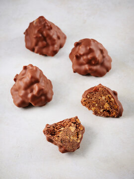 Chocolate-coated nut clusters with a bite taken out, revealing a crunchy texture inside. Ideal for dessert menus, social media posts, and snack packaging