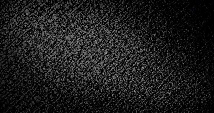 Abstract black texture. The slow, smooth diagonal movement of a dark, rough surface moving in a soft beam of light.