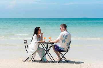 Obraz premium Romantic Couple Dining at Beachfront Table on Tropical Beach for Luxury Resort Honeymoon Promotion and Destination Travel Campaign