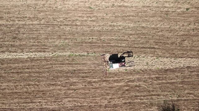 Aerial Drone View of Tractor Plowing Agricultural Field with Patterned Farmland
