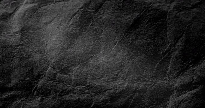Abstract black texture. The slow, smooth diagonal movement of a dark, rough surface moving in a soft beam of light.