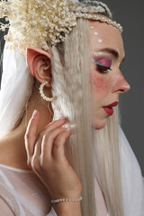 Naklejka premium Beautiful girl dressed as elf on grey background