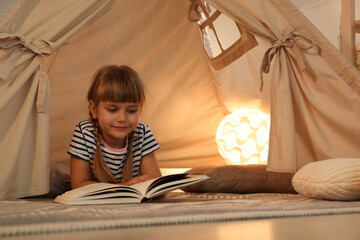 Little girl with book in wigwam at home © New Africa