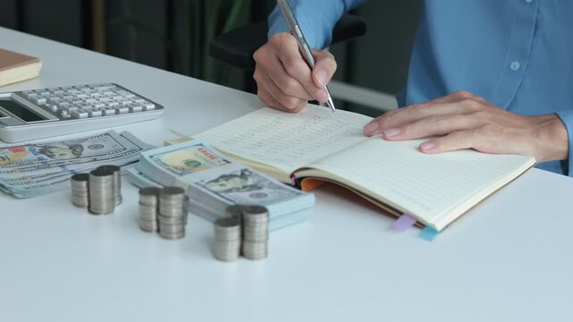 Three stacks of coins arrange separated on the table while businessman writing in a notebook. Concept for financial planning or budgeting