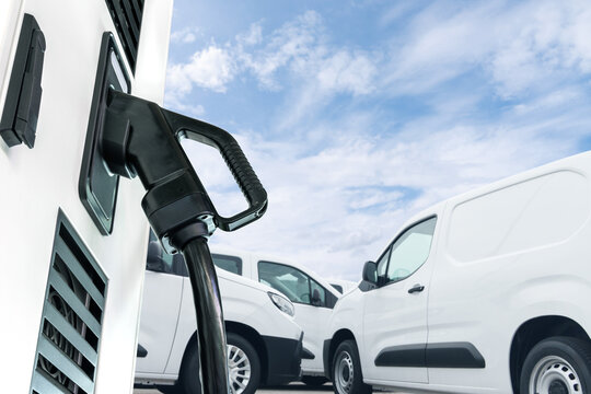 Electric vehicles charging station on a background of a row of vans. Green transportation concept