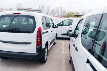 White delivery vans are parked in rows. Commercial fleet of vehicles