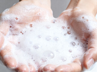 Fototapeta premium Close up of hands being washed with rich soap lather and clear running water in a bright modern bathroom sink for personal hygiene and health care