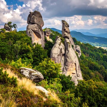 Large rock formations jut out from a lush green hillside under a cloudy sky