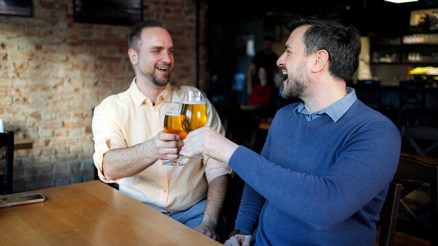 Friends share a toast with beer in a lively restaurant setting on a Saturday evening