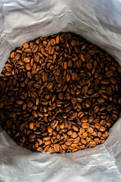 Coffee bean in a bag with a pour over coffee pot, grinder and kettle on a white tile surface 