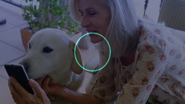 Senior woman tapping phone and petting dog chin on couch, dotted overlay showcasing tech content