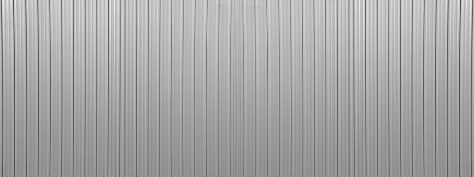 Silver tin iron corrugated wall with horizontal stripes from a metal profile of metal sheet Texture, background. grey white wall fence texture for backdrop galvanized gray facade.