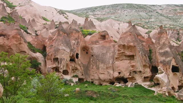 A scenic daytime shot of the stunning rock formations and ancient cave dwellings in the Zelve Open Air Museum, located in the Cappadocia region of Turkey. The unique geological features, known as "fai
