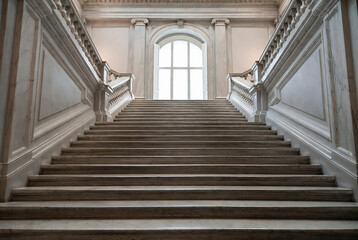 Naklejka premium A grand marble staircase leads upwards in a stately building.